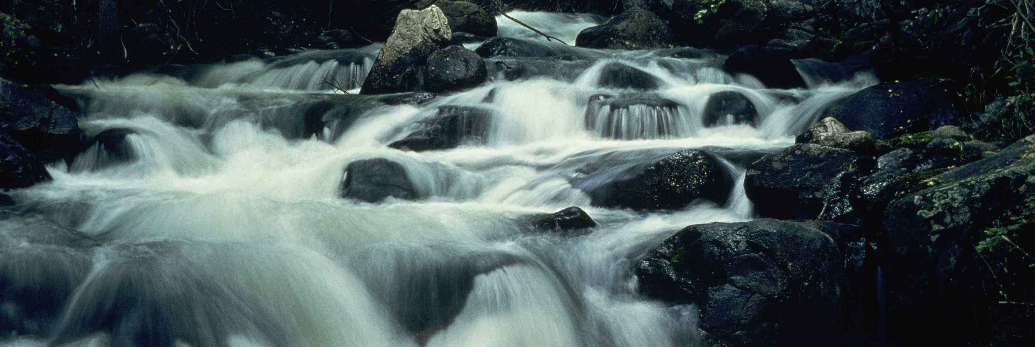 Fast mountain river makes a hazy waterfall / Public Domain